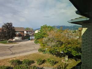 Expansive suburban streetscape featuring mature trees, a gently curving road, and a distant mountain range with snow-capped peaks