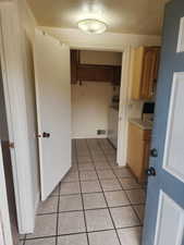 Ceramic tile flooring extends through this functional utility space, featuring built-in cabinetry, an overhead light fixture, and a white appliance