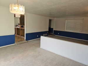 Carpeted living area featuring a decorative chandelier and a half-wall partition