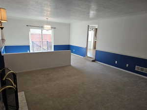 Expansive carpeted living area with a half-wall partition and crown molding
