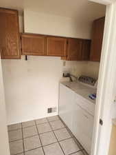Laundry area featuring wood cabinetry, tiled flooring, and white walls