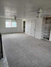 Spacious room featuring light gray carpet flooring, white walls, and a built-in shelving unit