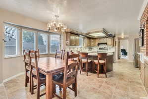 Open-concept kitchen and dining area featuring tile flooring, a bay window, a kitchen island with bar seating, wood-finish cabinetry, and stainless steel appliances