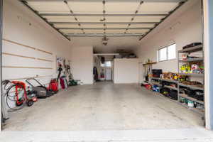 Spacious garage featuring a concrete floor, overhead garage door, built-in shelving, and transom window