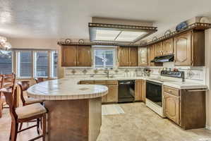 Kitchen featuring a curved tile-top breakfast bar, wood cabinetry, tile flooring, and integrated appliances