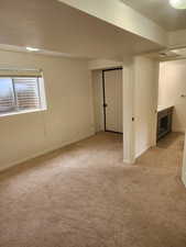 Carpeted interior space with a window featuring blinds, a built-in light fixture, and a doorway leading to a bathroom with a vanity