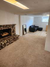 Cozy room featuring a stone-clad fireplace with hearth, soft carpeted flooring, and recessed ceiling lighting
