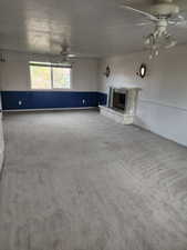Spacious room featuring a stone-clad fireplace with hearth, multiple ceiling fans, and a window providing natural light