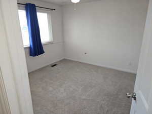 Carpeted room featuring a window with horizontal blinds, white walls, and white baseboards