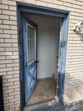 Brick exterior with a partial light blue door featuring a window insert and decorative paneling