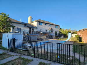 Rear exterior featuring a multi-level deck, a covered patio, and an in-ground pool area with safety fencing