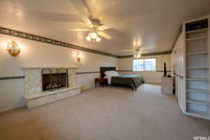 Spacious room featuring a stone-clad fireplace, built-in shelving, and two ceiling fans with integrated lighting