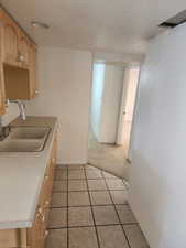 Kitchenette featuring wood-finish cabinetry, a double basin sink with a chrome faucet, and a laminate countertop