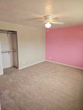 Spacious room featuring neutral carpeting, a ceiling fan with integrated lighting, and a closet with shelving and hanging rods