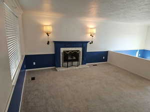 Carpeted living area featuring a prominent fireplace with a blue mantel and marble-look surround