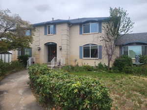 Brick exterior residence featuring a curved driveway, arched entry with wrought iron security door, and blue window shutters