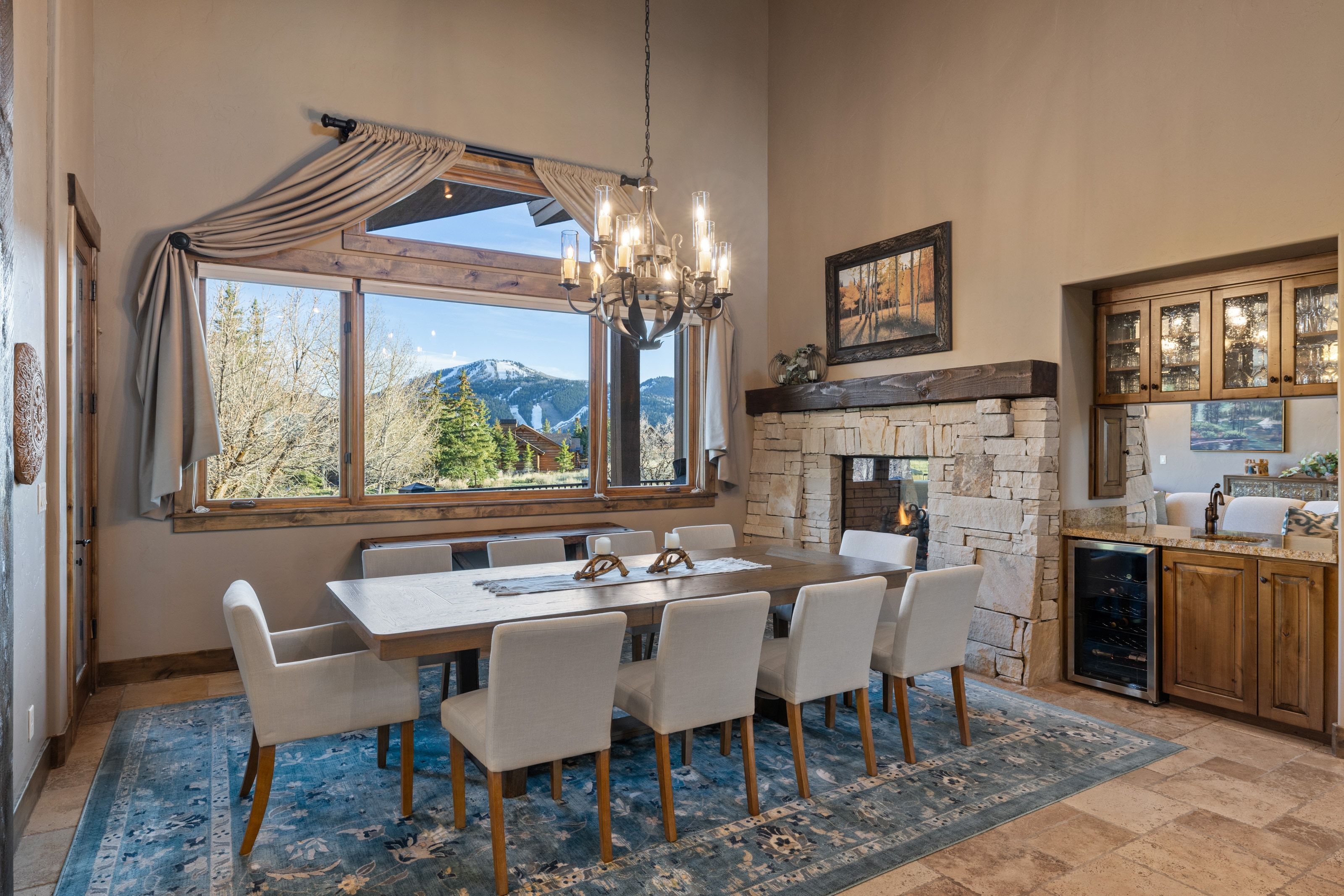 Dining room featuring beverage cooler, stone tile flooring, a mountain view, a fireplace, and hanging lights