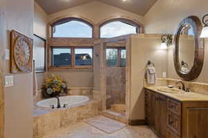 Full bath featuring vanity, walk in shower, a bath, and a textured wall