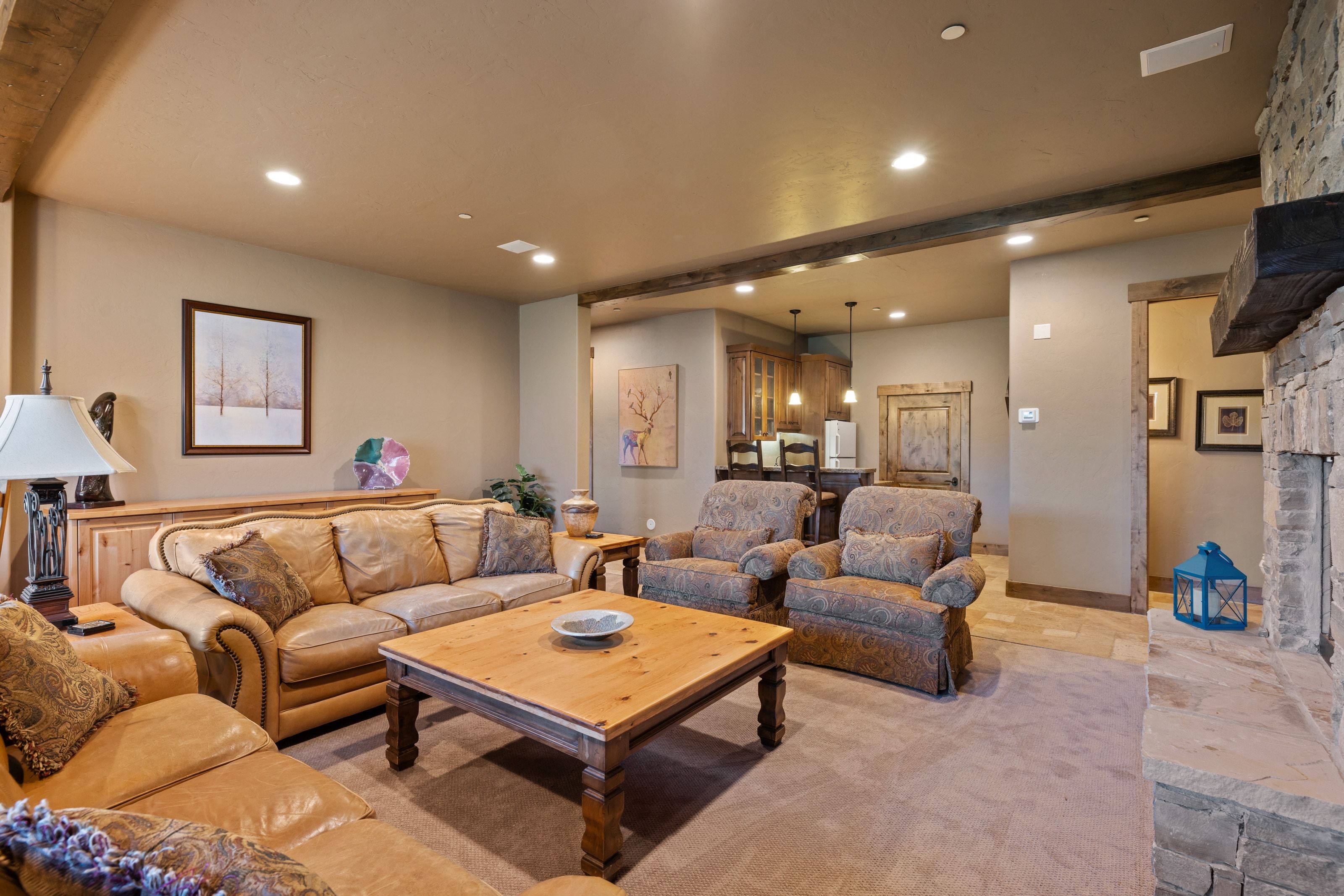 Living area with stone tile flooring, beamed ceiling, a fireplace, and recessed lighting