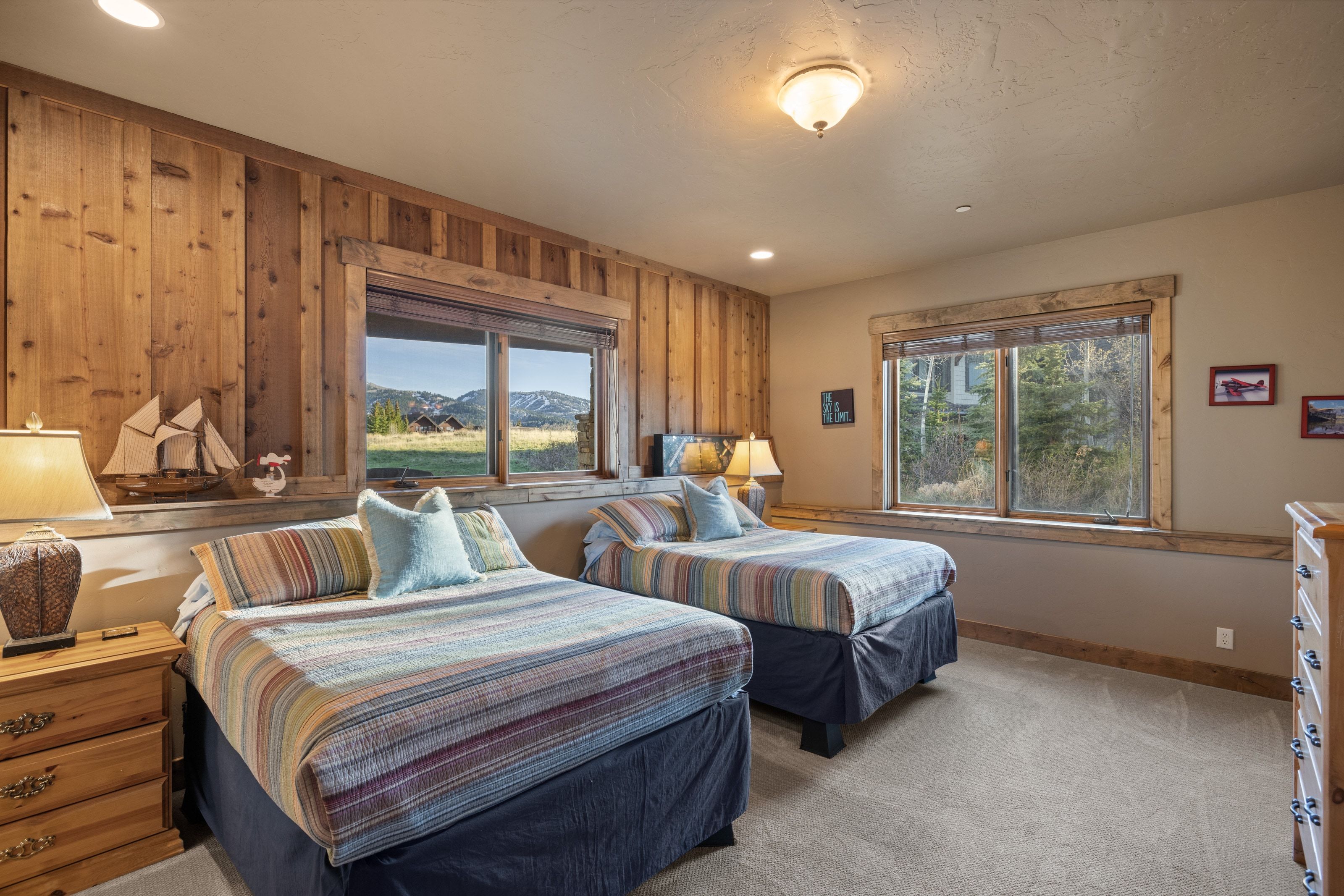 Bedroom featuring multiple windows, light colored carpet, wooden walls, recessed lighting, and a mountain view