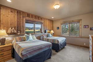 Bedroom featuring multiple windows, light colored carpet, wooden walls, recessed lighting, and a mountain view