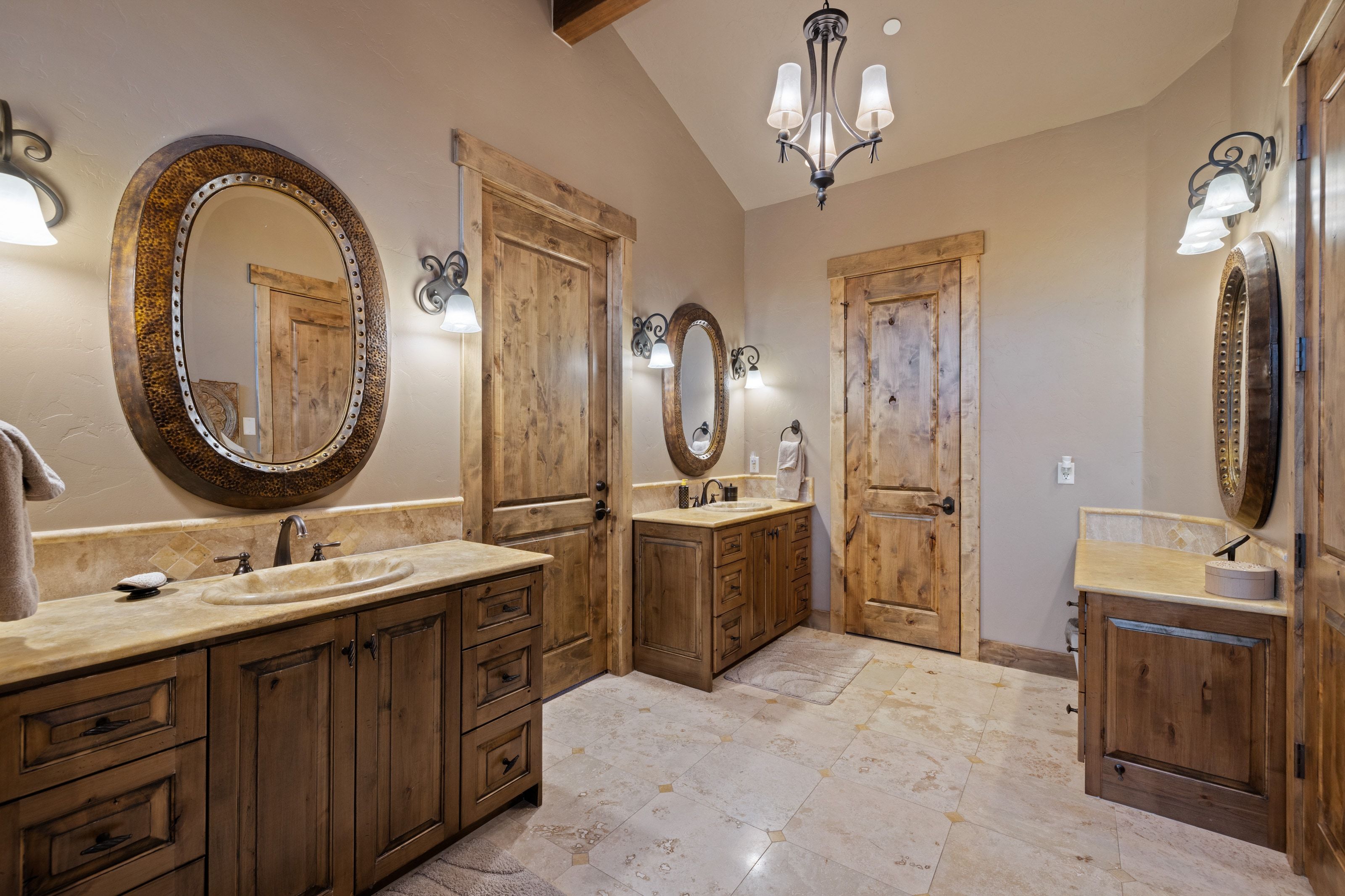 Full bath featuring two vanities, vaulted ceiling with beams, and a chandelier