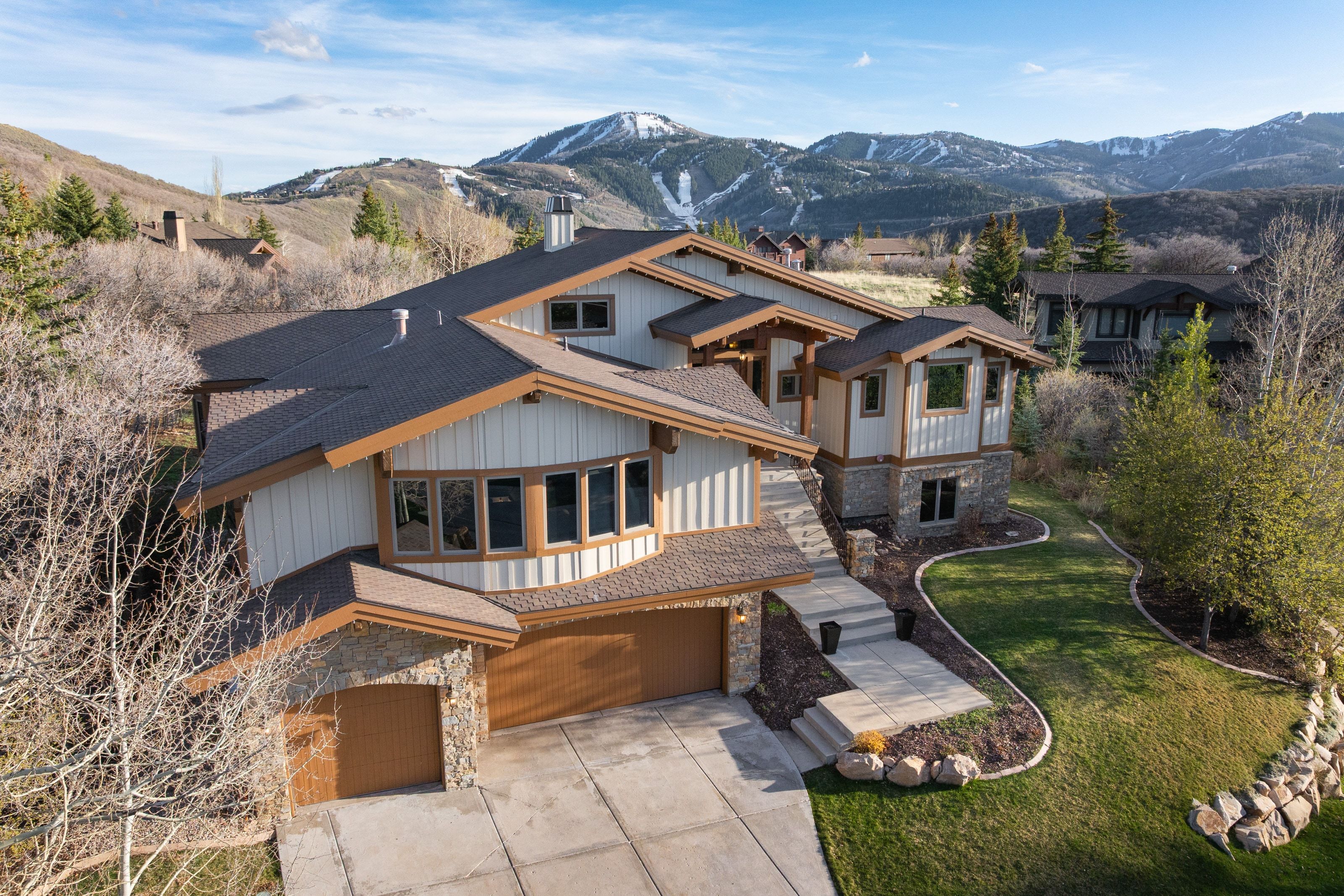 View of front of property featuring stone siding, a garage, concrete driveway, a mountain view, and a front yard