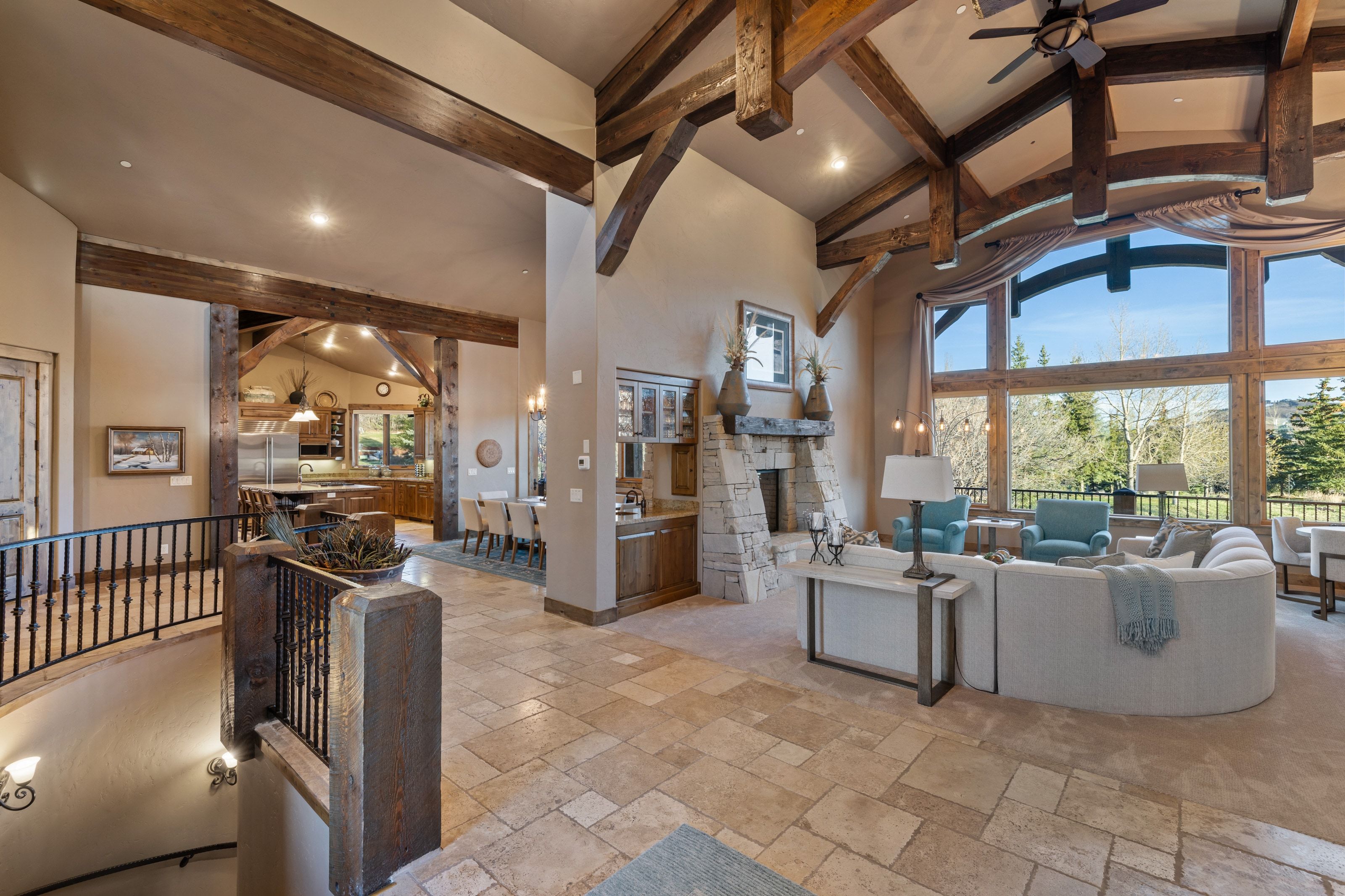 Living room featuring stone tile flooring, a fireplace, vaulted ceiling, a ceiling fan, and recessed lighting