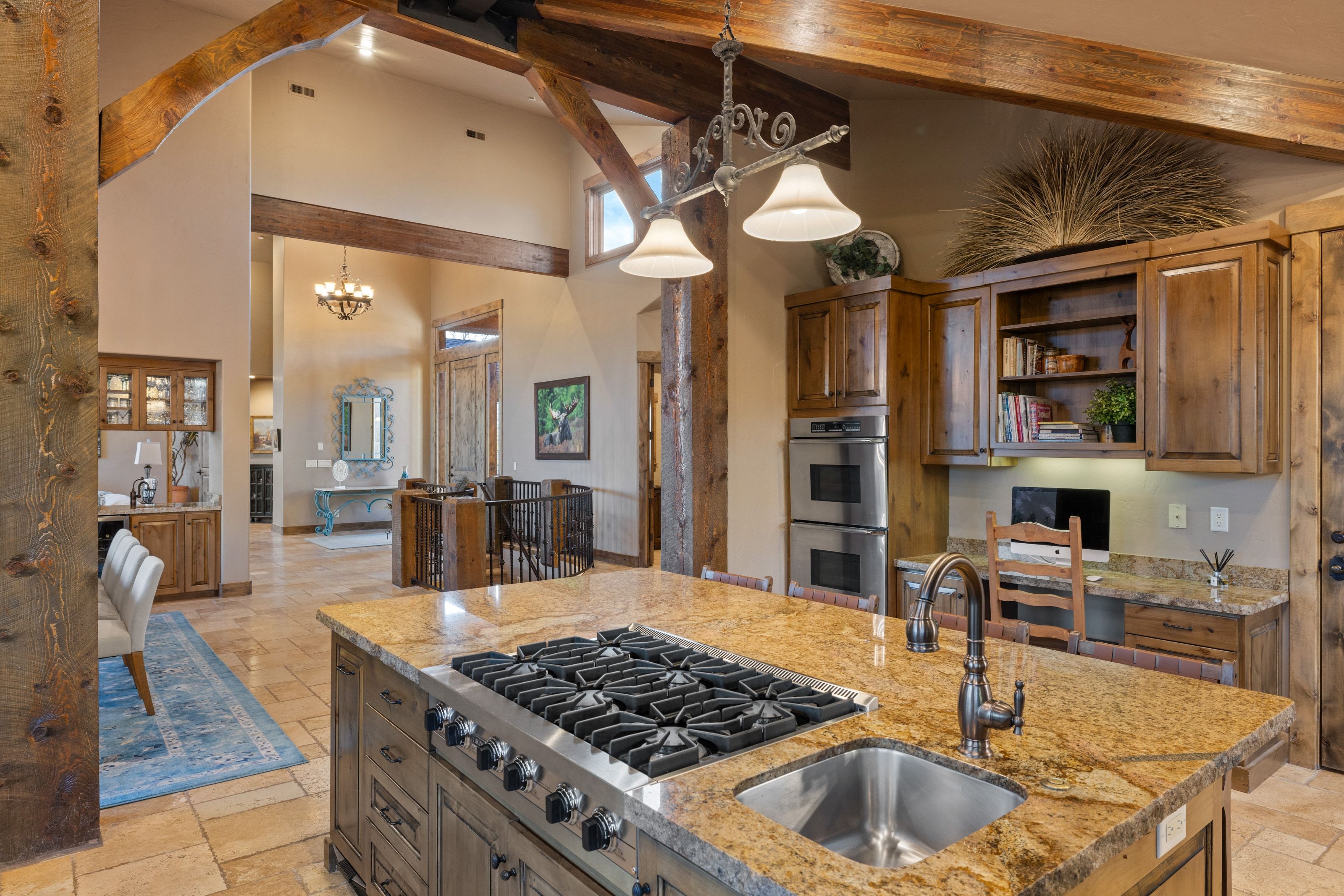Kitchen with stone tile floors, stainless steel appliances, light stone counters, open shelves, and lofted ceiling