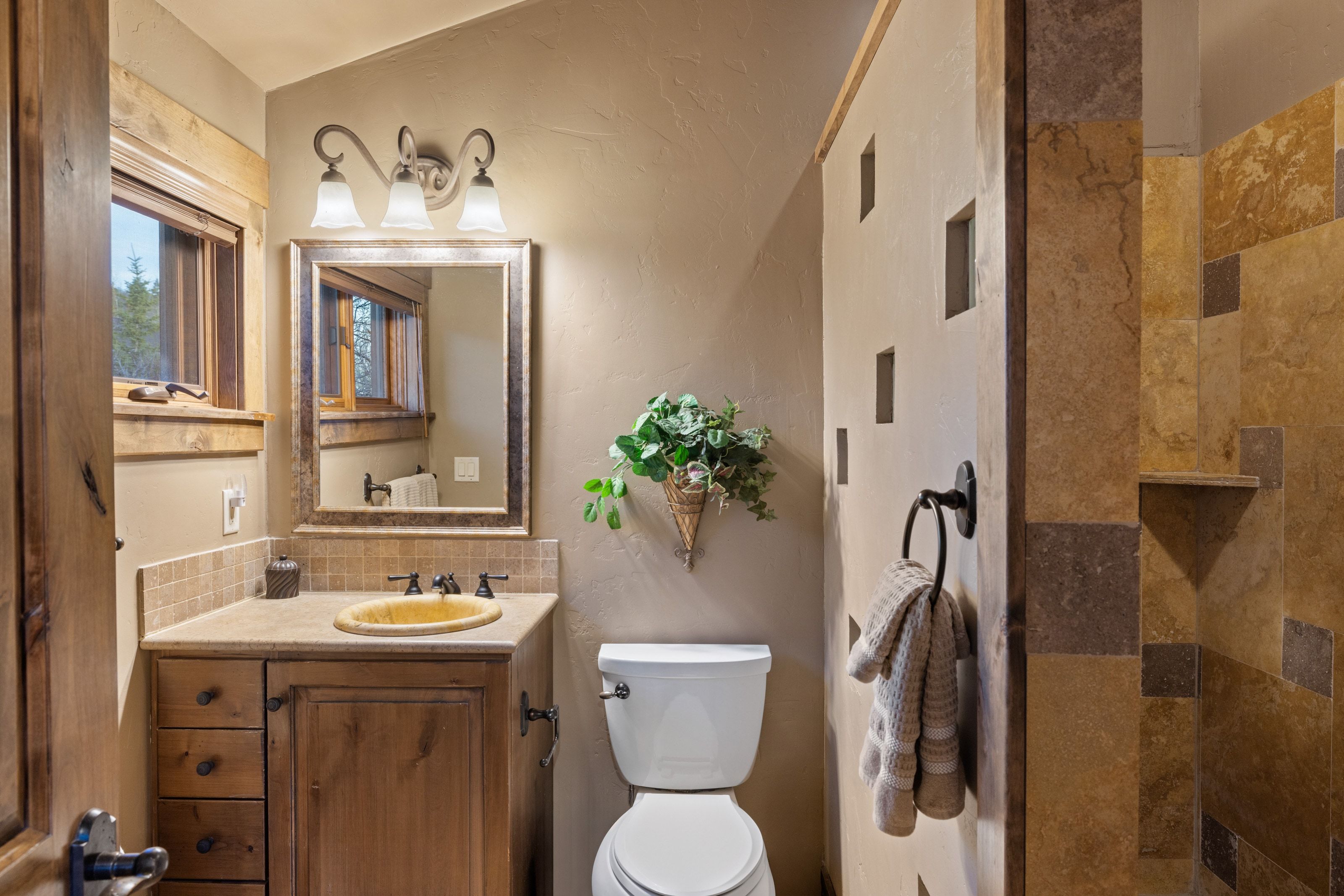 Bathroom with decorative backsplash, vanity, tiled shower, and a textured wall