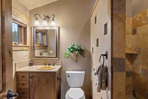 Bathroom with decorative backsplash, vanity, tiled shower, and a textured wall