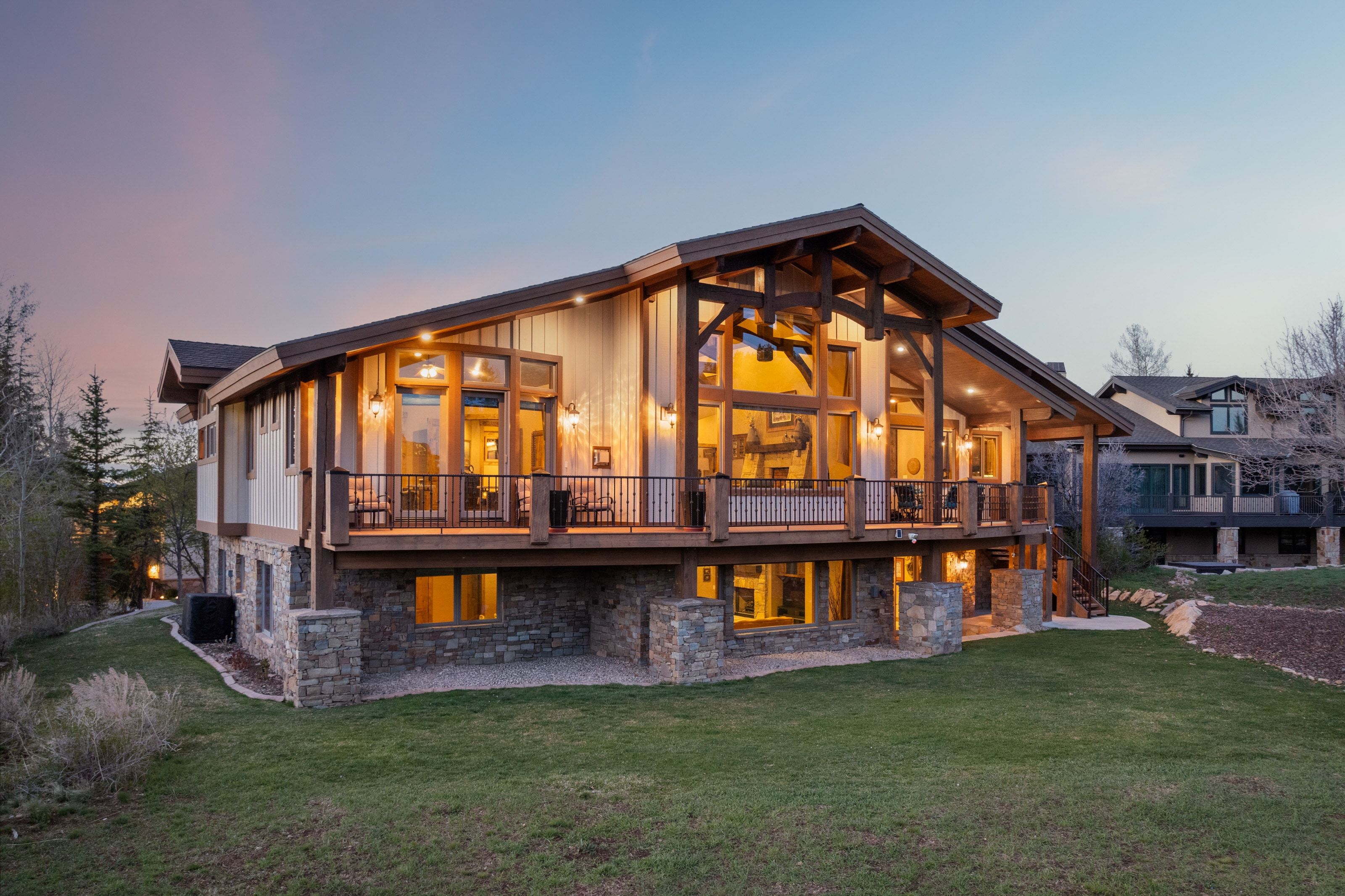 Back of property with stone siding, a yard, a deck, and a patio