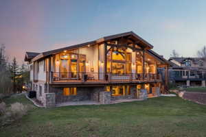 Back of property with stone siding, a yard, a deck, and a patio