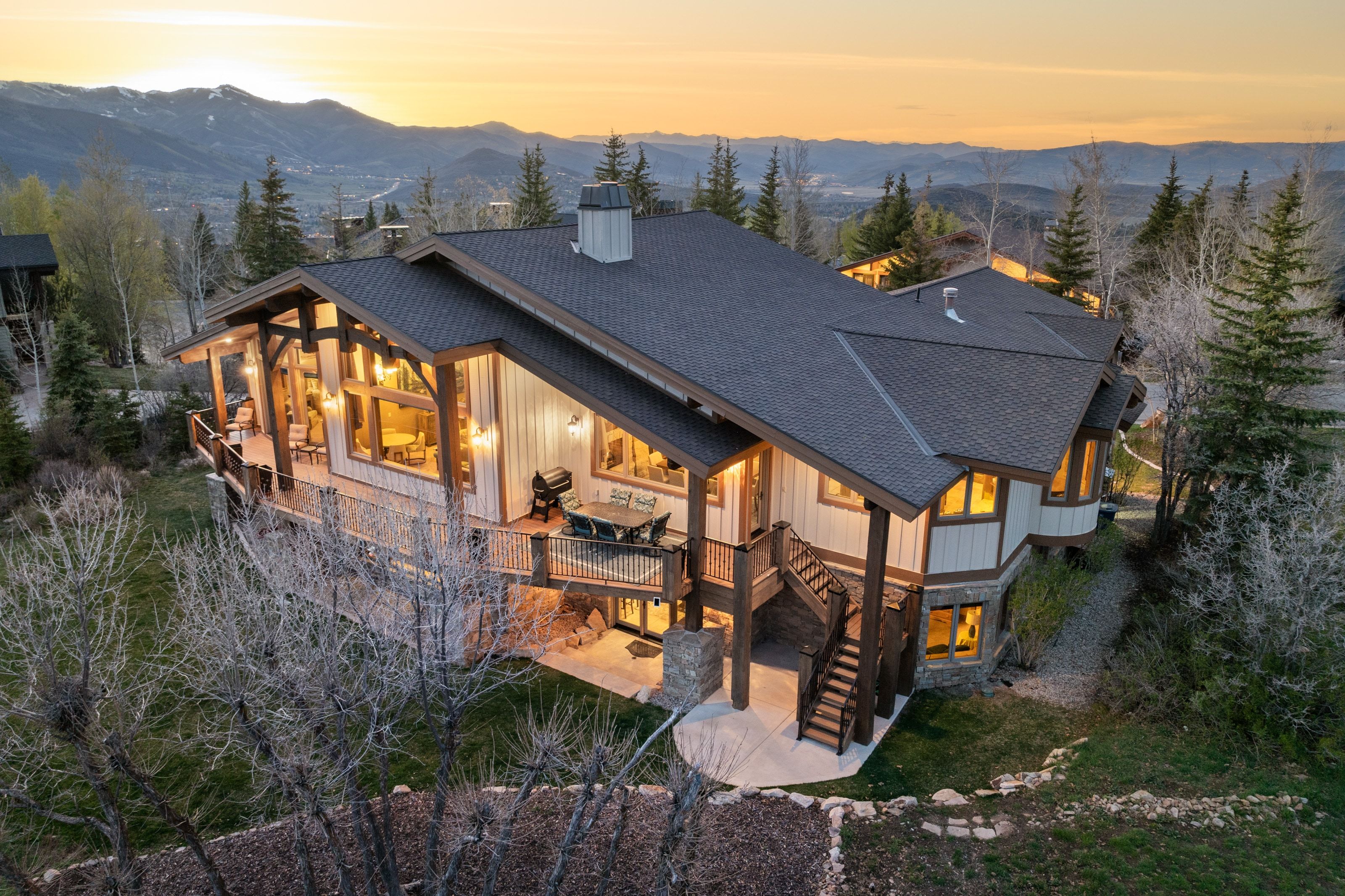 Back of property at dusk featuring roof with shingles, a patio area, a deck with mountain view, and board and batten siding