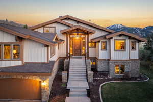 View of front facade featuring a shingled roof, stone siding, board and batten siding, and a garage