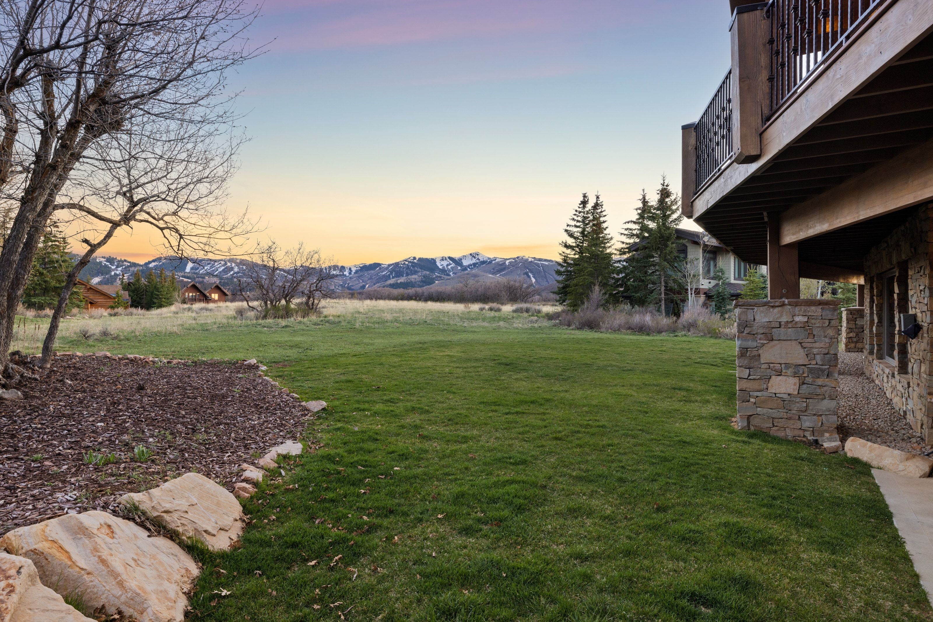 View of grassy yard with a mountain view, a balcony, and a patio