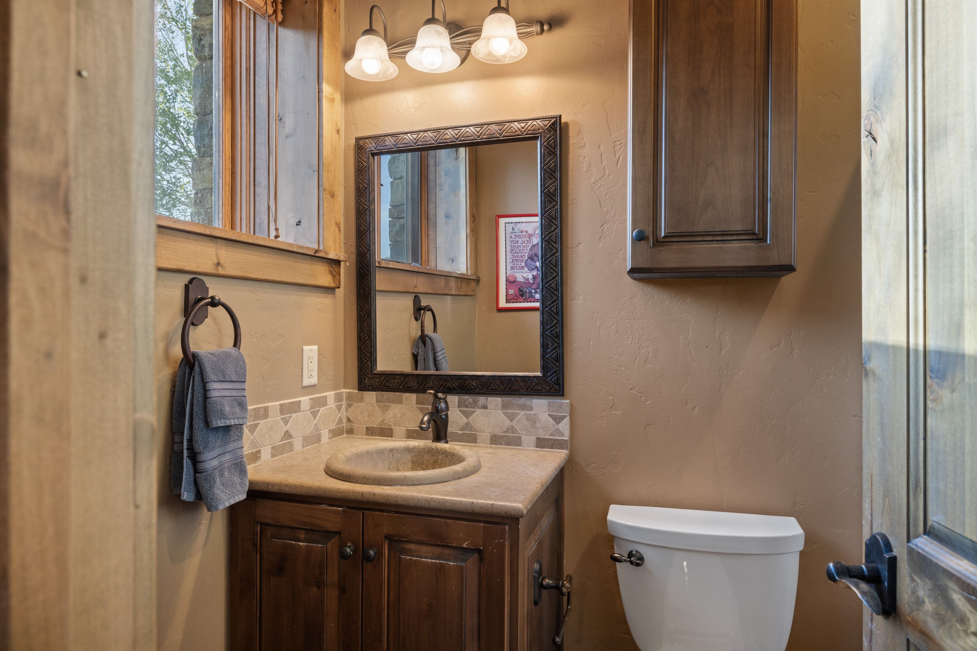 Bathroom featuring a textured wall, decorative backsplash, and vanity