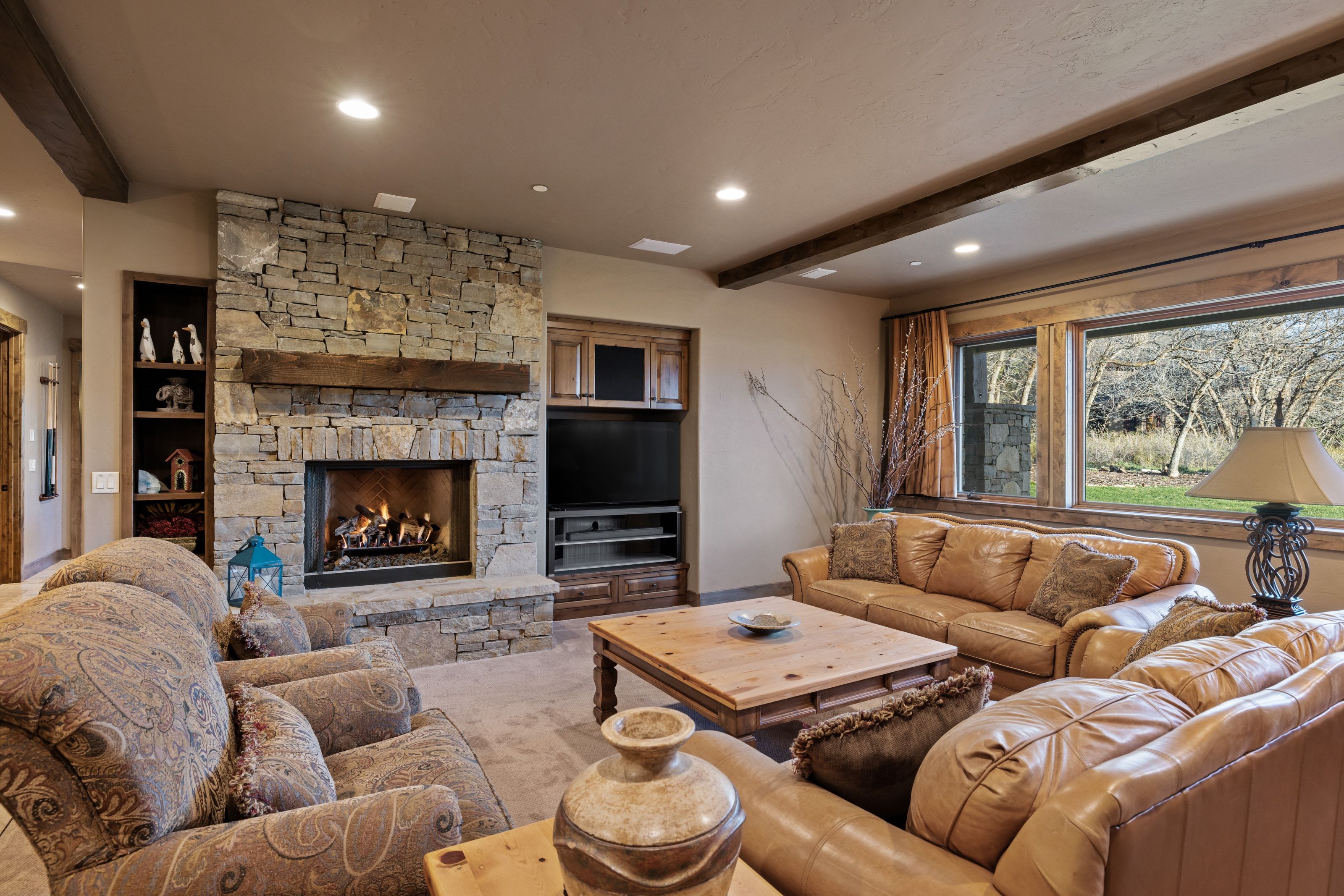 Living room featuring recessed lighting, beamed ceiling, a stone fireplace, and carpet