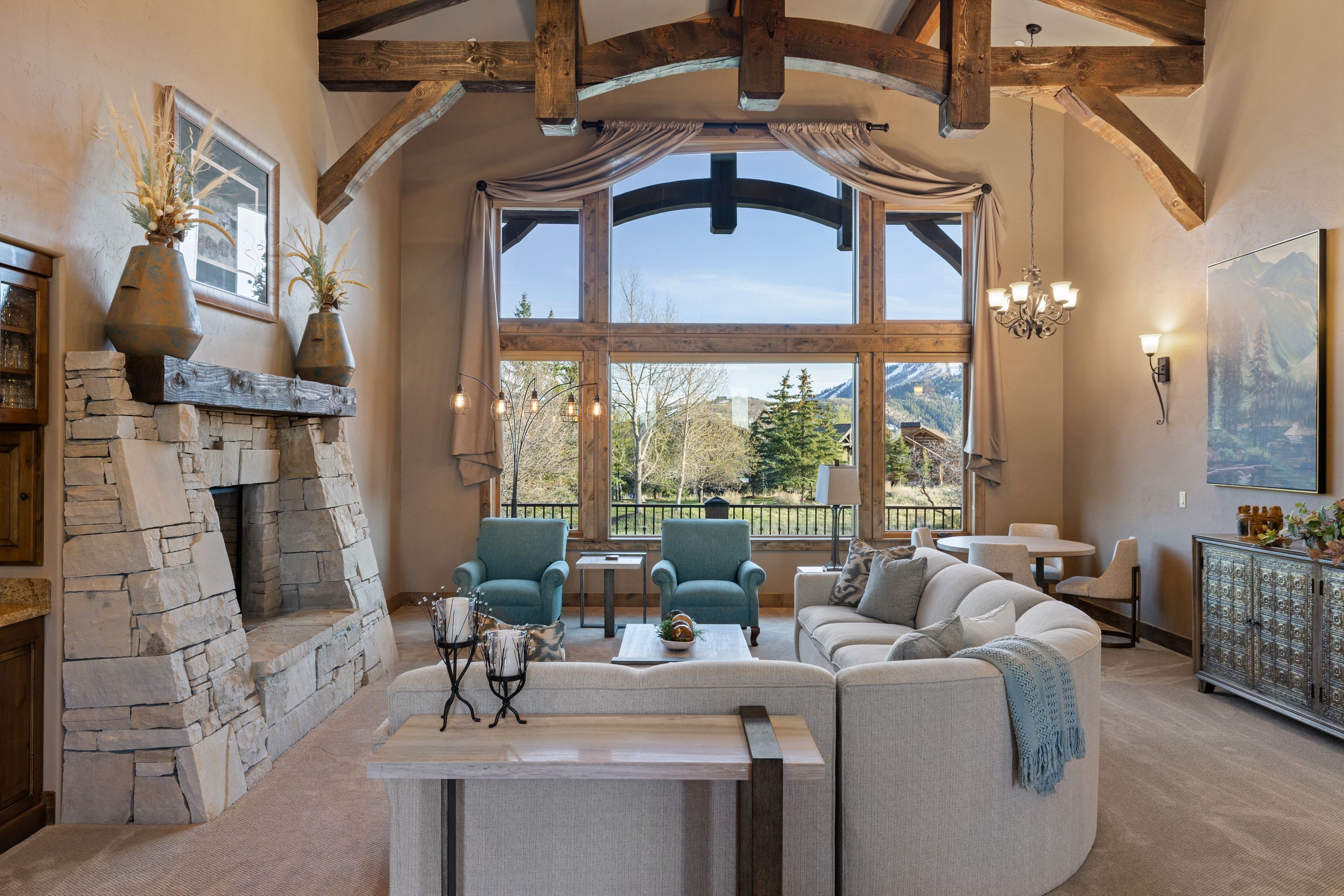 Carpeted living room featuring a stone fireplace, healthy amount of natural light, and suspended lighting