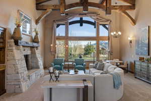 Carpeted living room featuring a stone fireplace, healthy amount of natural light, and suspended lighting