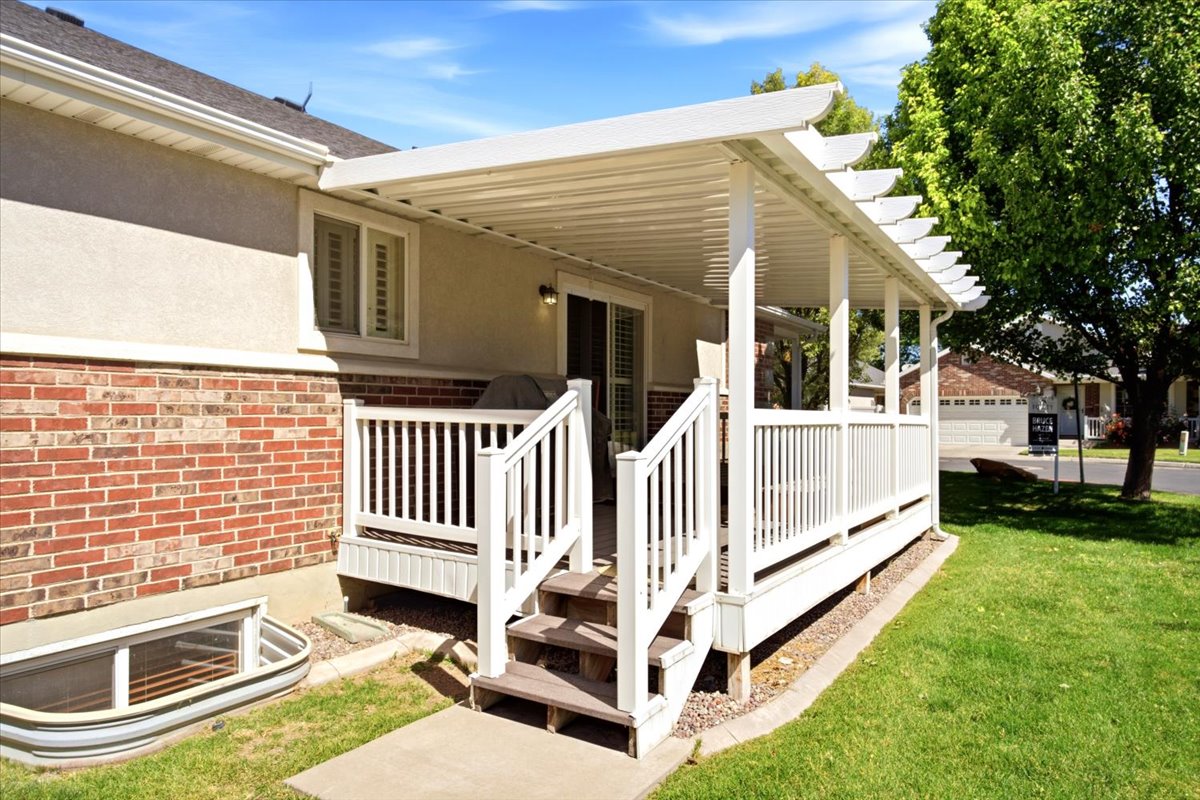 Outdoor patio with white railing and steps, featuring a full overhead covering and decorative pergola accents