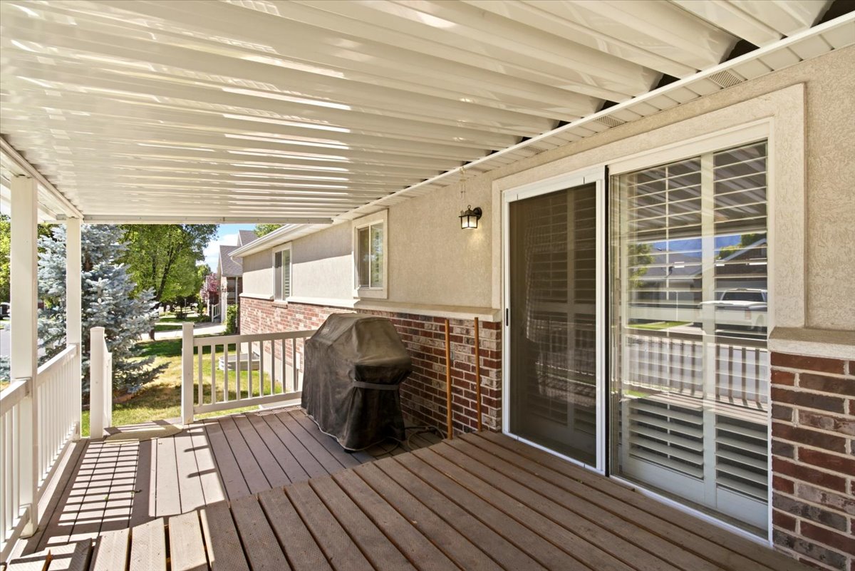 Covered wood-finish patio featuring white railing