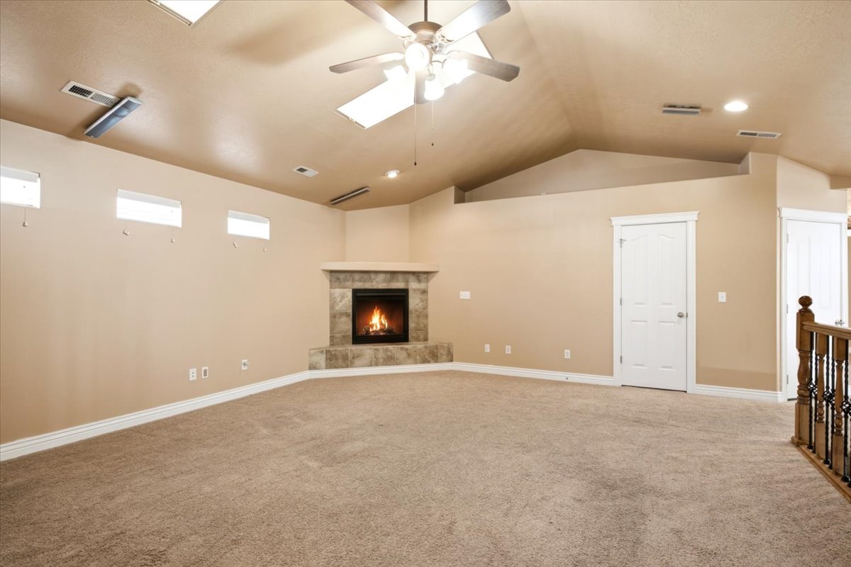 Spacious room featuring vaulted ceilings, a ceiling fan, and recessed lighting