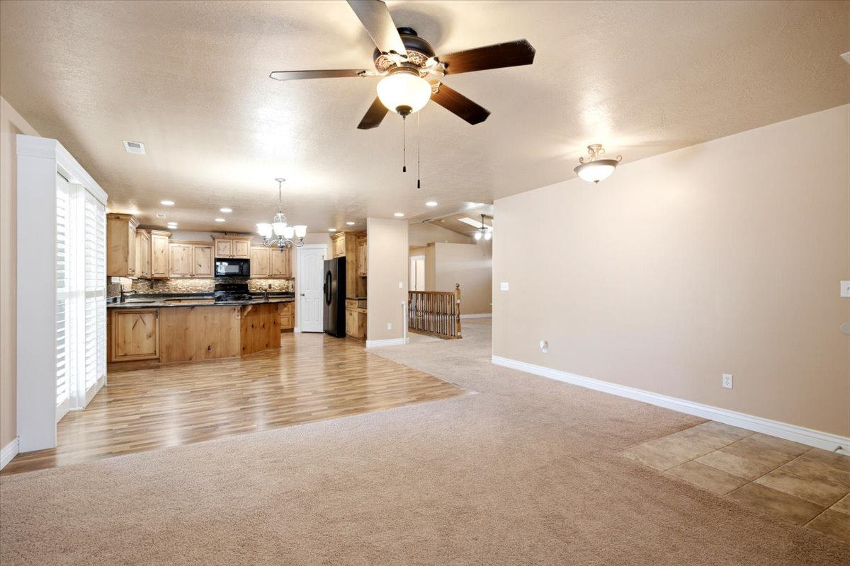 Open-concept interior featuring wood-finish flooring, recessed lighting, ceiling fan, and a kitchen with wood cabinetry and dark countertops