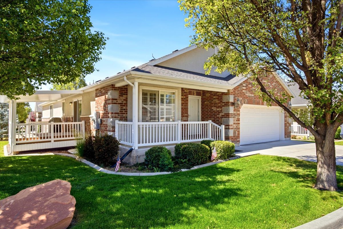 Brick facade residence with an attached garage, featuring a covered front porch with white railings