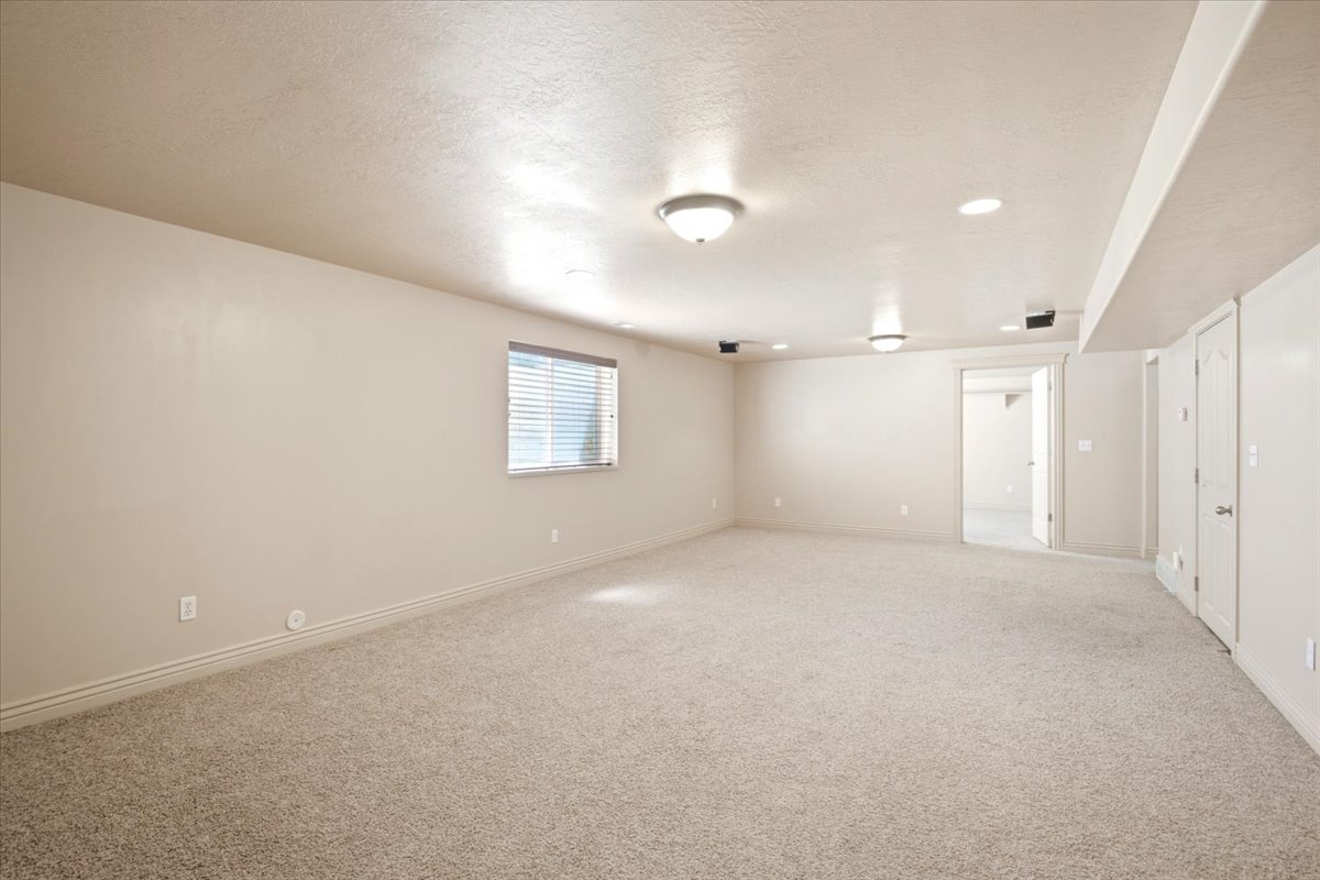 Spacious room featuring neutral paint, light-toned carpet flooring, recessed lighting, and a window with blinds