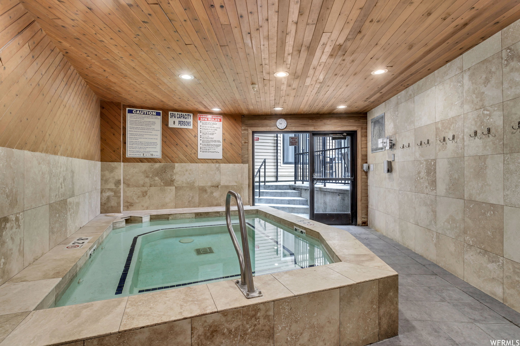 Indoor spa featuring a tiled surround, wood-finish ceiling, recessed lighting, and access to exterior stairs