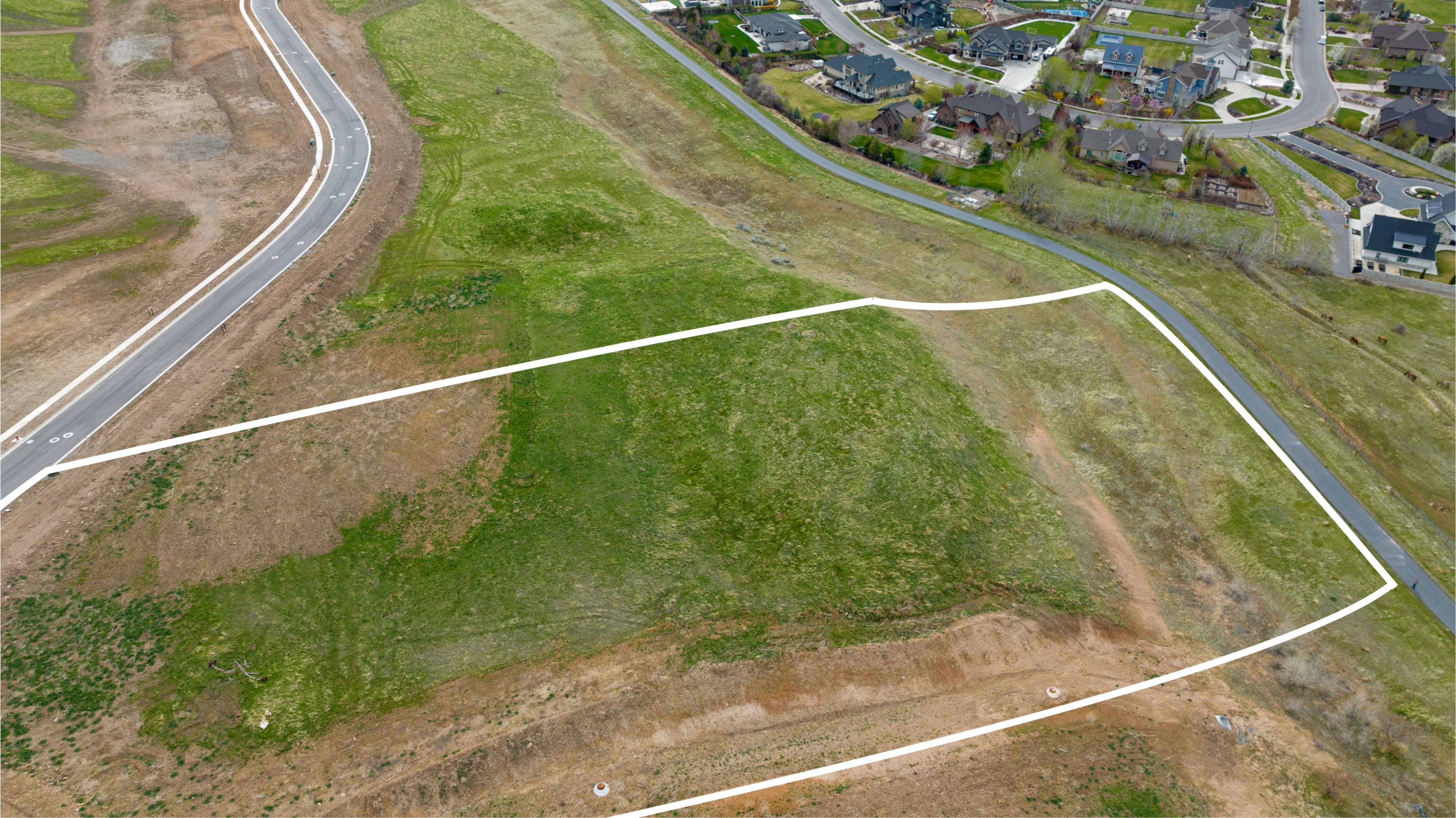 Expansive land parcel featuring existing paved roadways and partial grass coverage