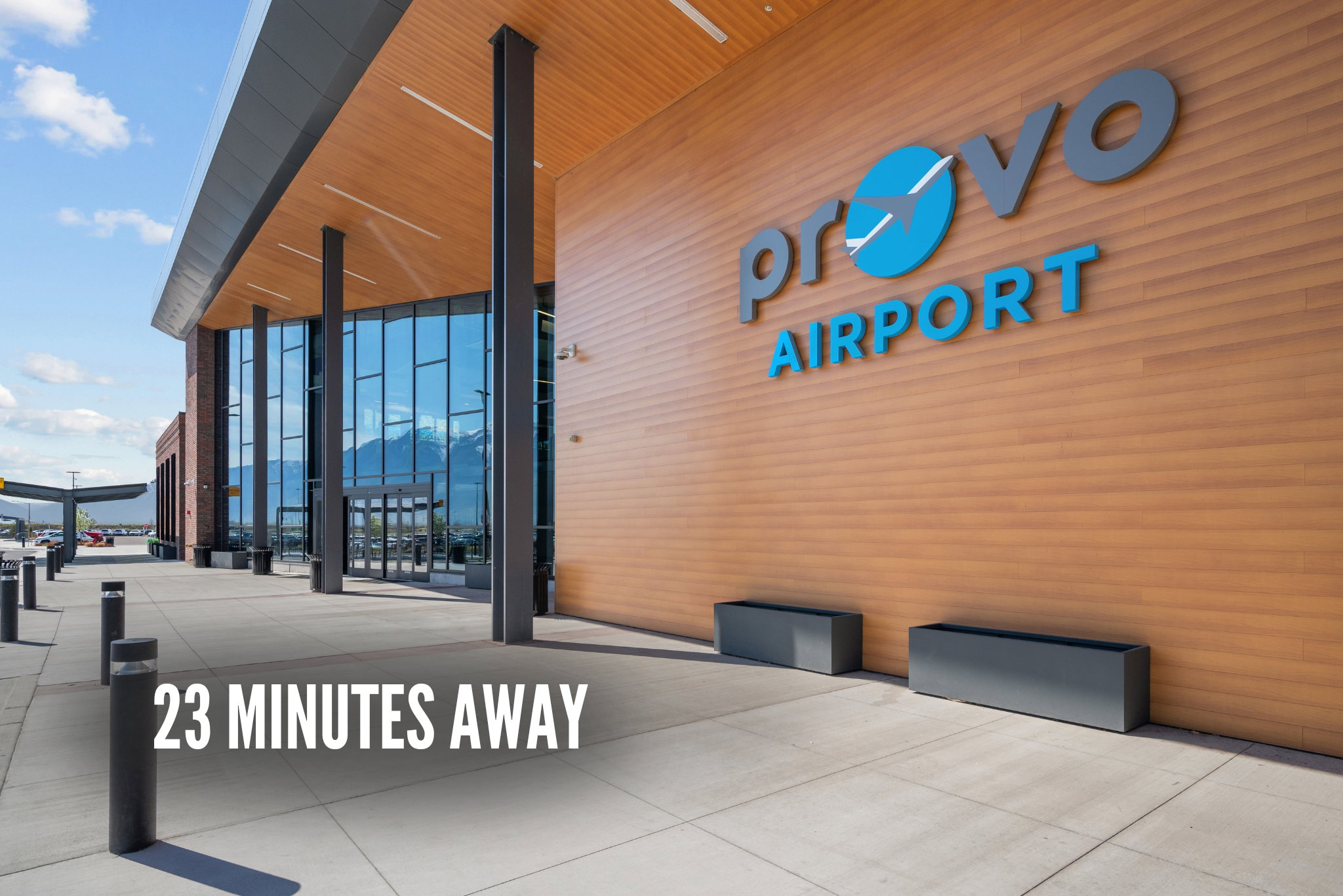 Modern airport terminal featuring extensive glass curtain walls, wood-finish paneling, concrete walkways, and contemporary architectural elements