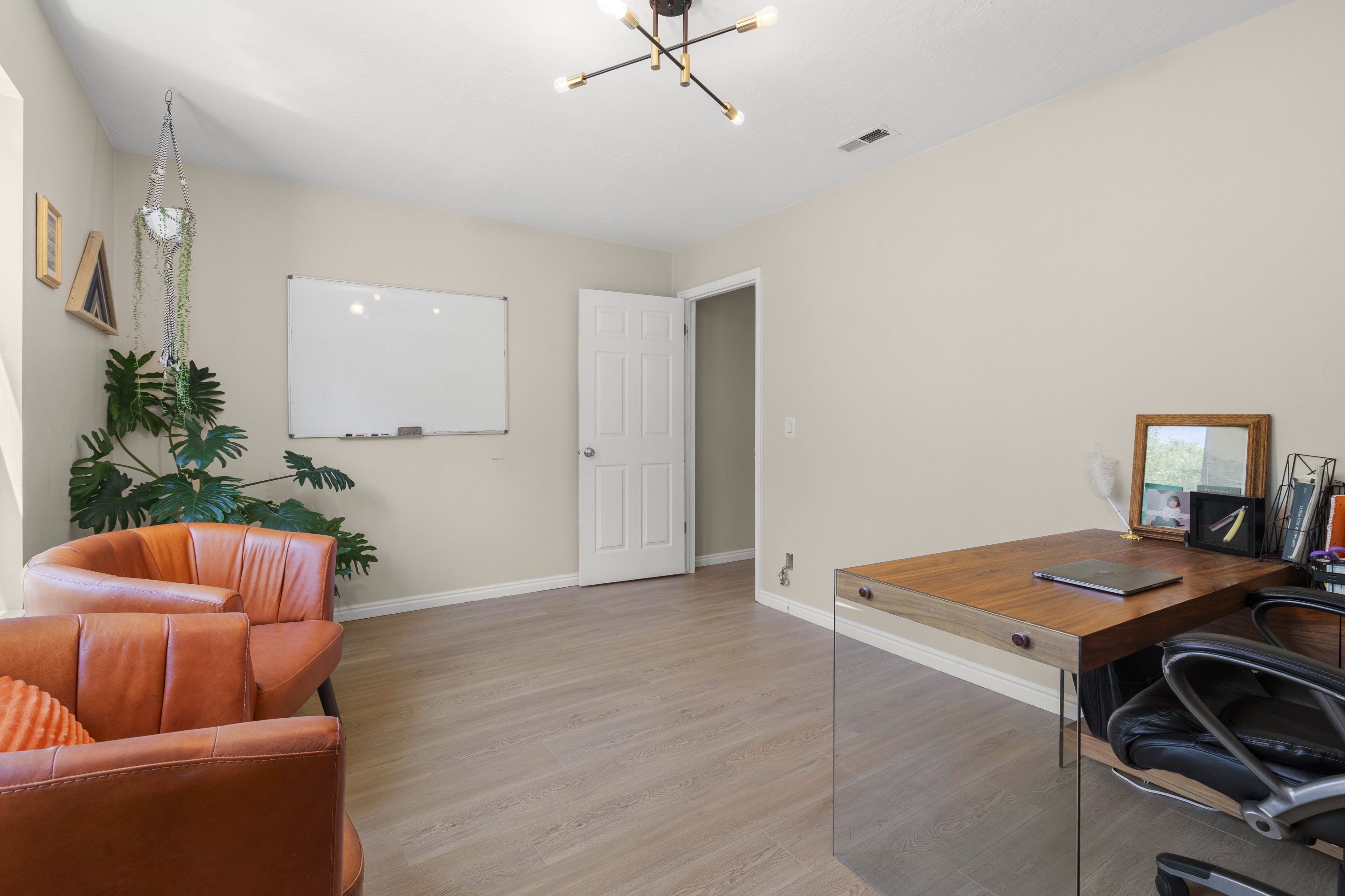 Spacious room featuring wood-finish flooring, neutral-toned walls, and a contemporary ceiling light fixture